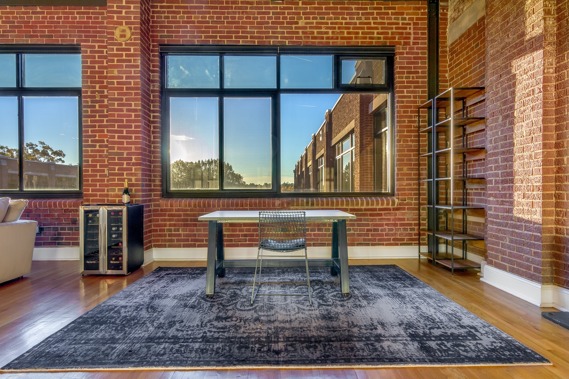 Office area open to living room red brick walls light wood floors large black trim windows