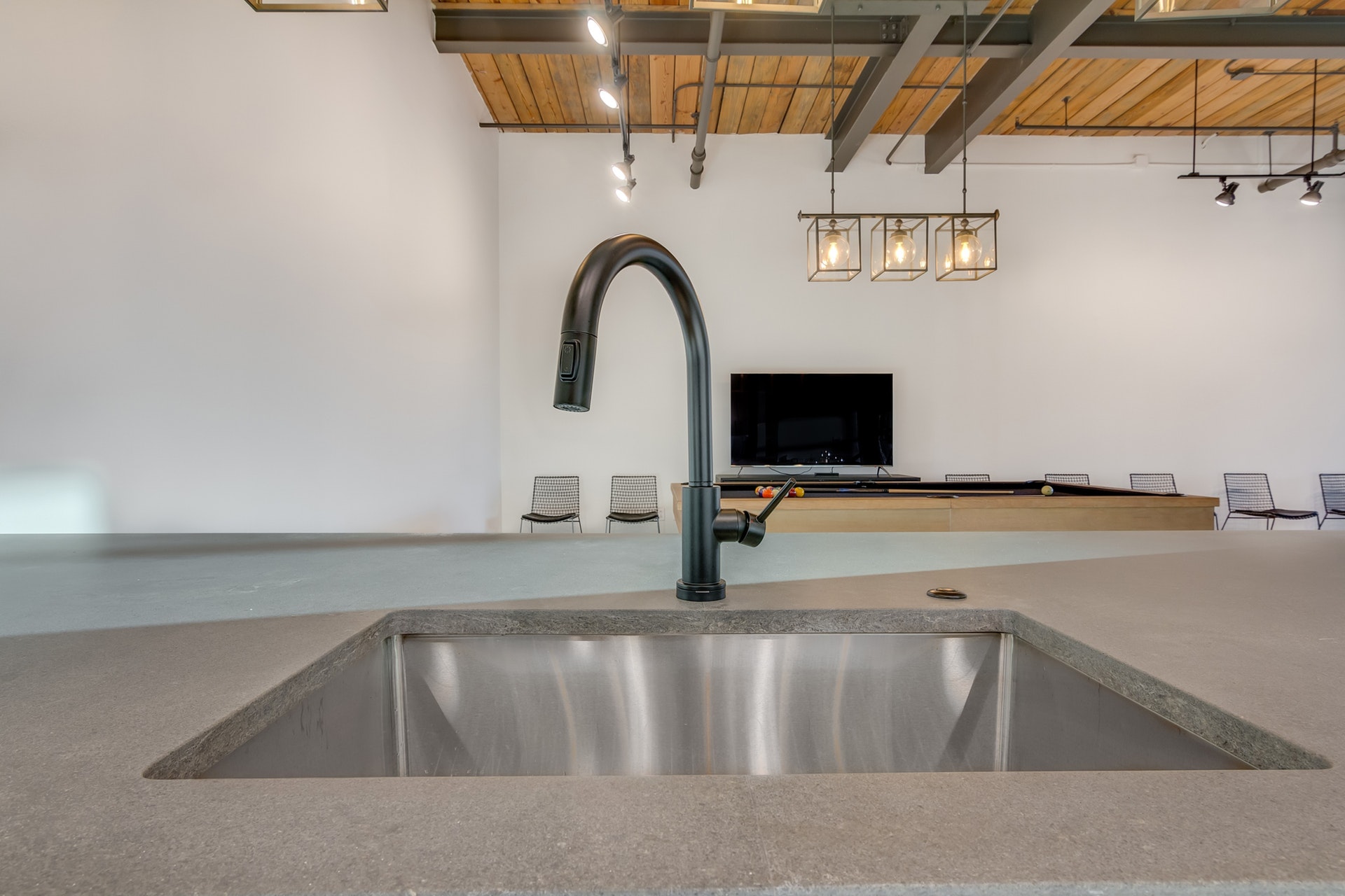 Kitchen sink with stainless steel basin and black faucet white walls wood ceiling