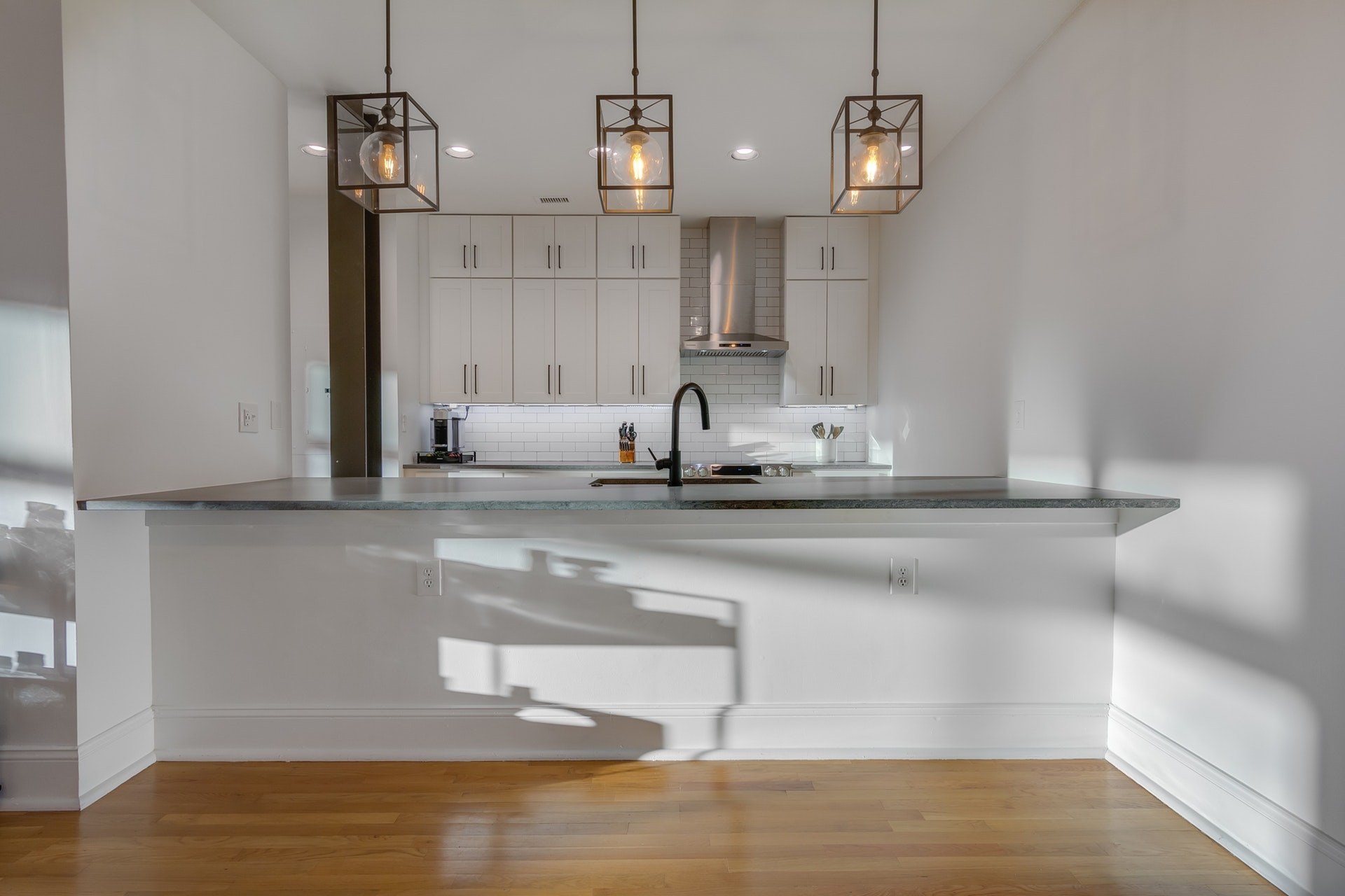 Kitchen with white walls light wood floors black countertop white subway tile backsplash