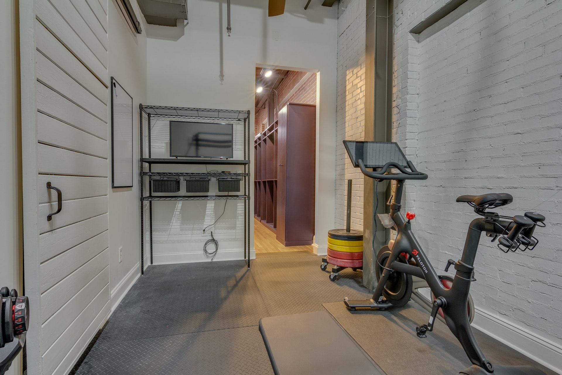 Exercise room with white walls white sliding barn door gray flooring Peloton bike