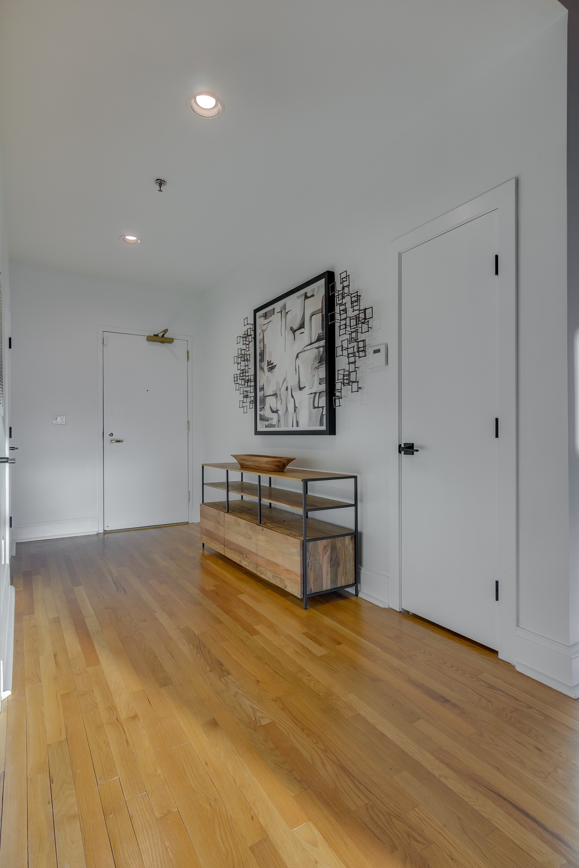 Entryway with white doors white walls light wood floors