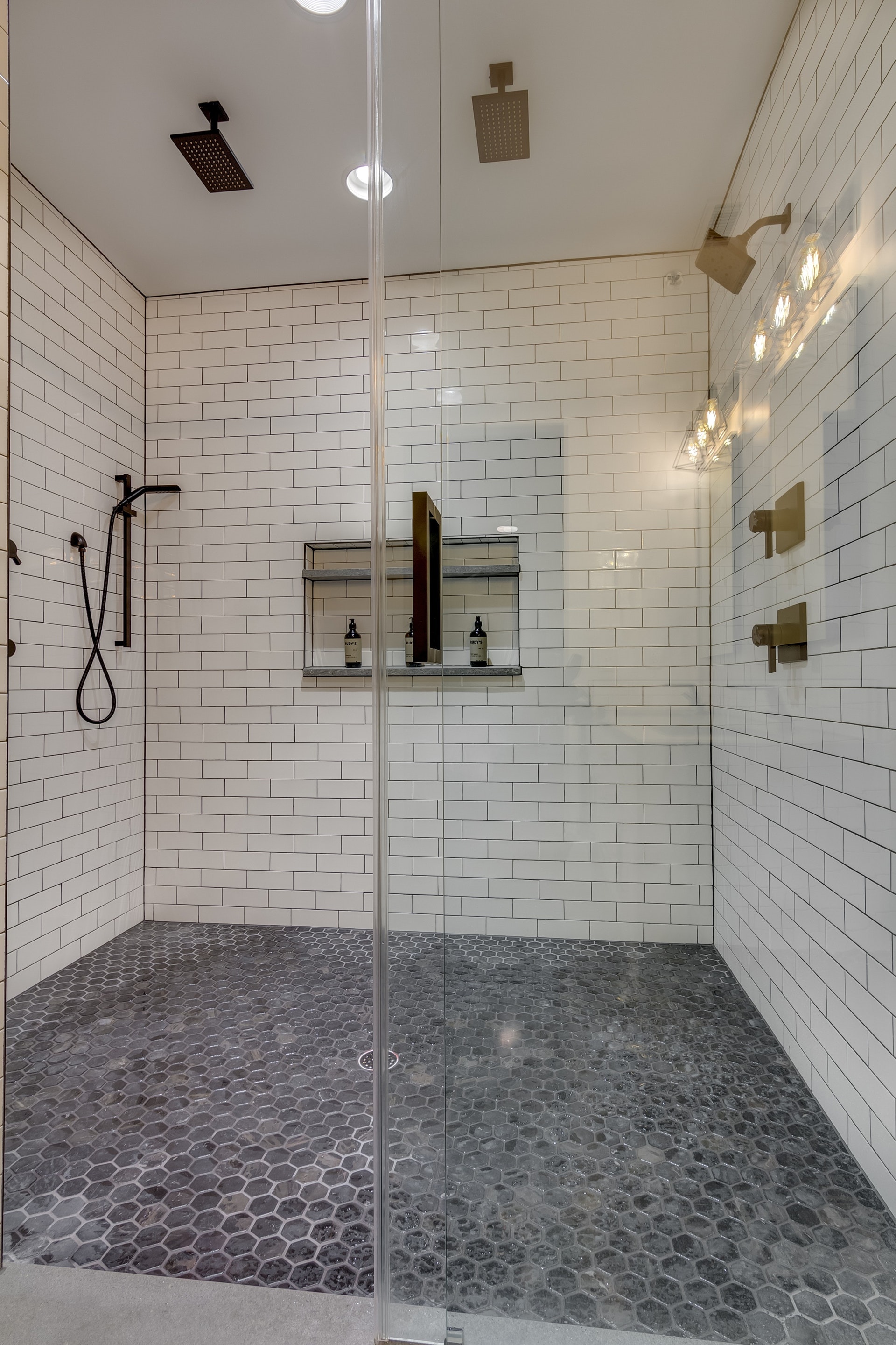 Large white tile with dark grout walk in shower glass door gray hexagon tile floor