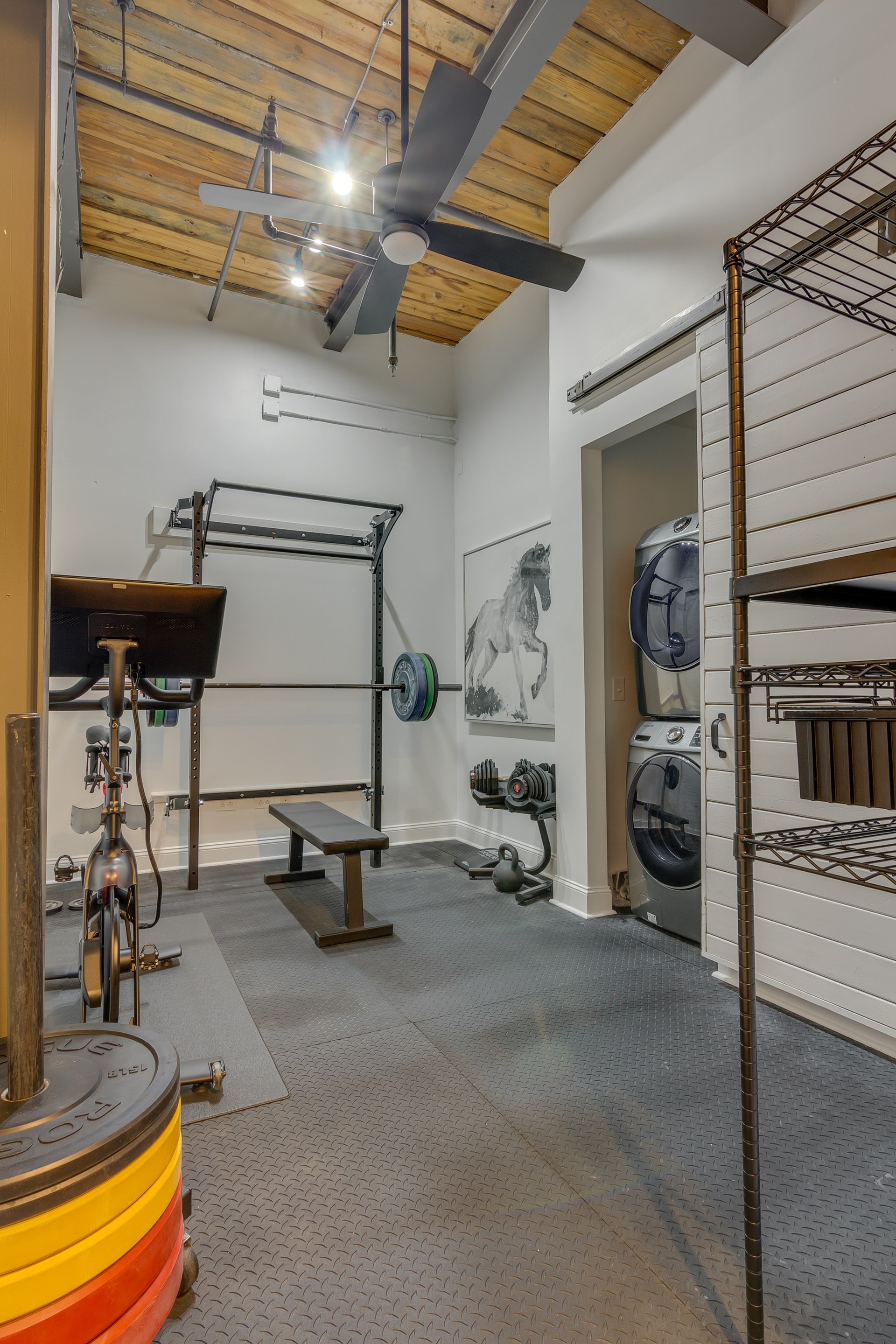 Home gym with white walls white barn sliding barn door wood ceiling exposed pipes exercise equipment
