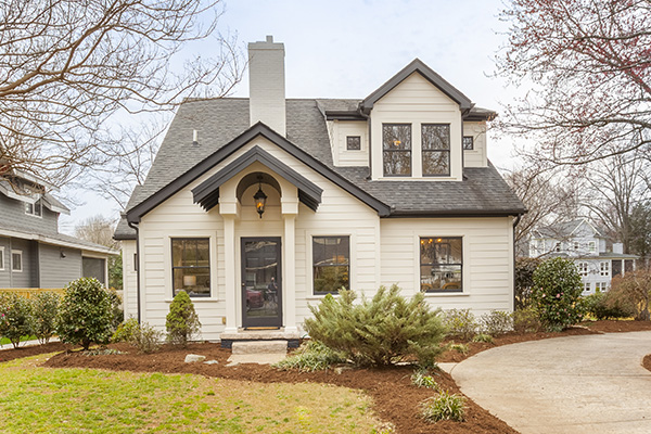 Two story home with white siding black trim windows black shingle roof white brick chimney circular driveway