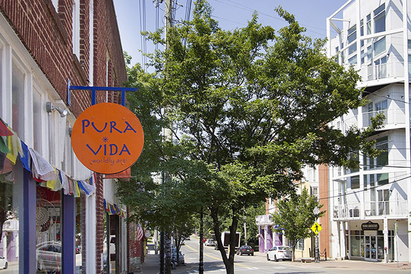 Brick building with orange and purple Pura Vida sign and tree in front