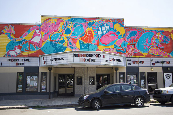 Neighborhood Theatre with mural on top of building car parked in front