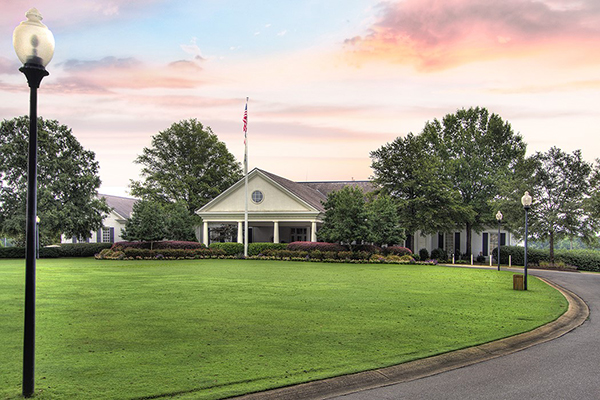 Country Club building with sunset sky large green grass circular driveway lined with lamp posts