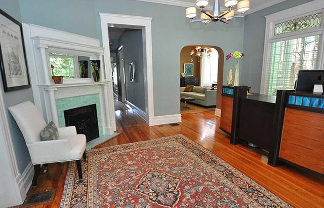 Savvy Co Real Estate Office lobby with brown wood floors blue walls white trim wood front desk blue tile fireplace