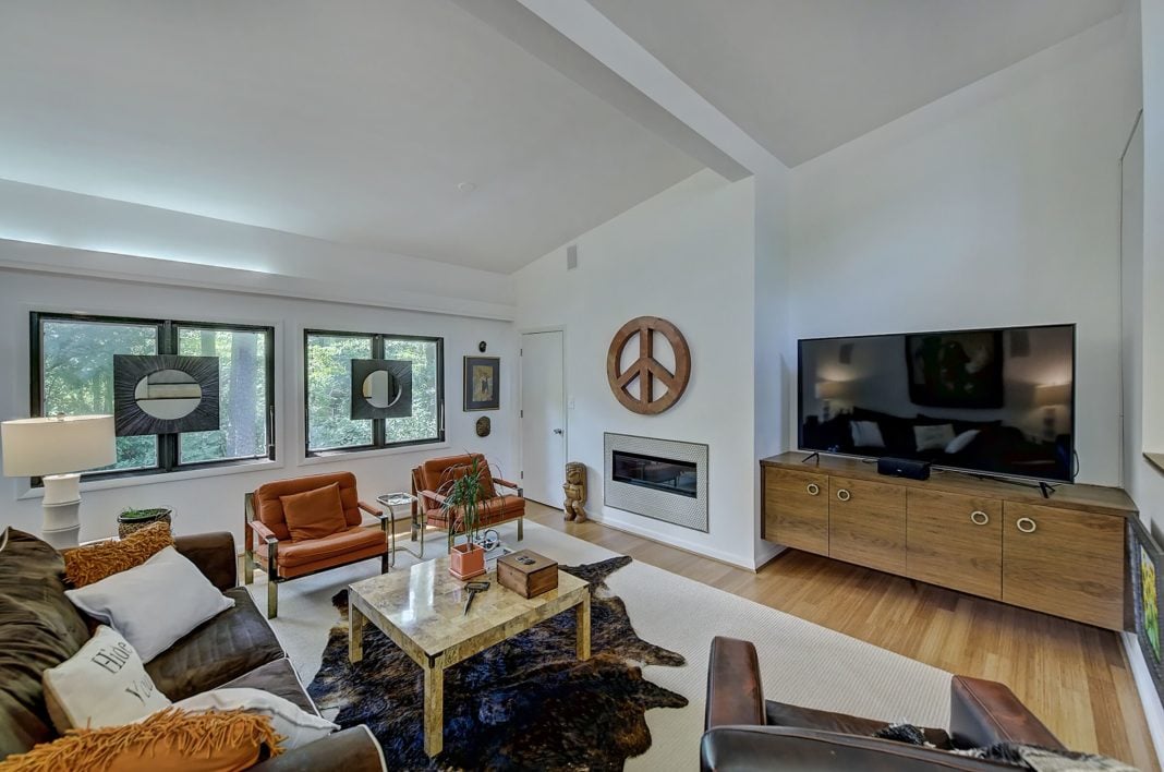Living room with white walls black trim windows light wood floors built in fireplace