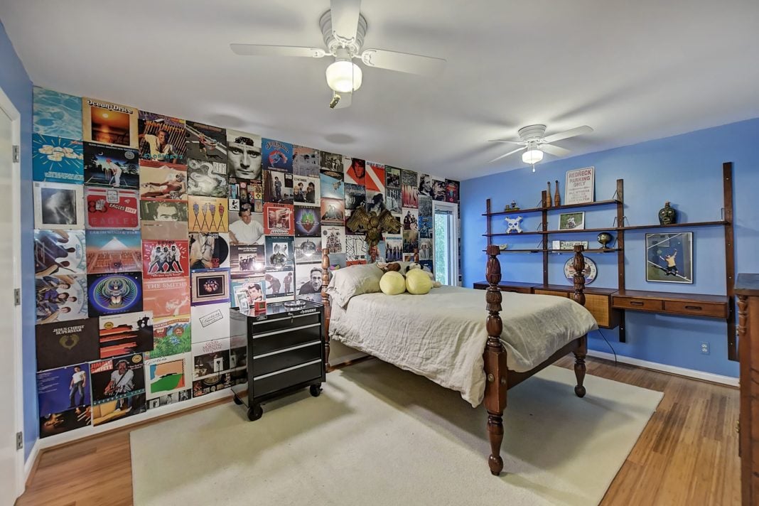 Bedroom with blue walls light wood floors white ceiling fans dark wood furniture album cover mural on back wall