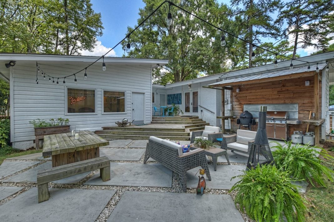 Backyard with white siding and wooden steps cement and gravel floor covered grill area
