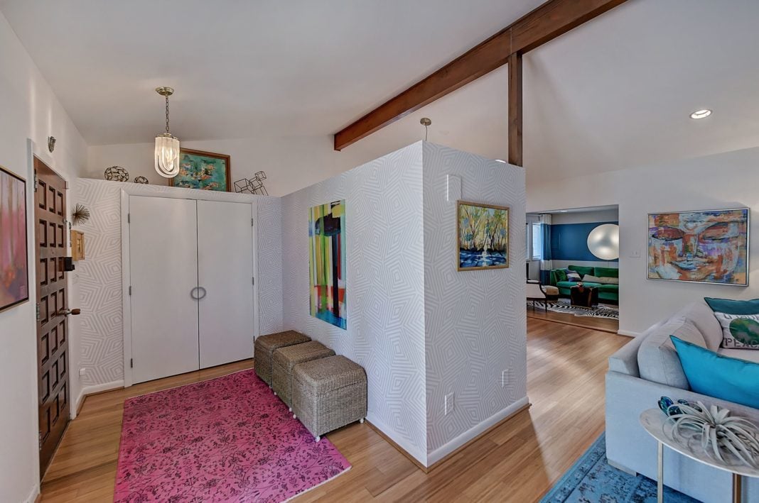 Entryway and living room white wallpaper walls dark wooden beams on ceiling light brown wood floors double door closet