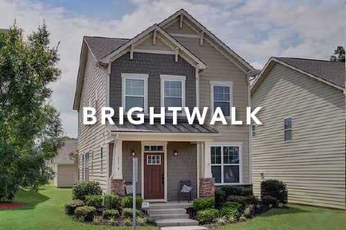Gray home with a mix of siding and shingles with front porch and brown front door with the word Brightwalk typed over the image