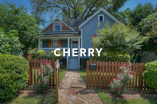 Home with blue siding brown shutters brown picket fence cobblestone walkway and the word Cherry typed over the image in white font