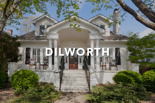 Home with white siding black shutters dark wood front door white brick steps and the word Dilworth typed over the image in white font