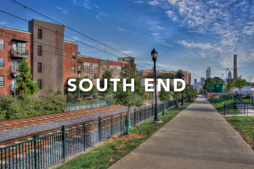 Clear blue sky with a walking path next to train tracks and brick apartment building and Charlotte skyline in background with the words South End typed over the image
