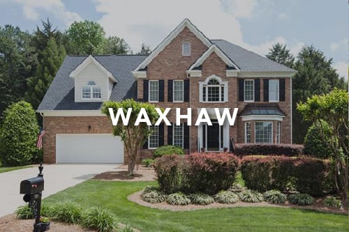 Waxhaw Brown brick home with black shutters black front door two car garage landscaped front yard and the word Waxhaw typed over the image