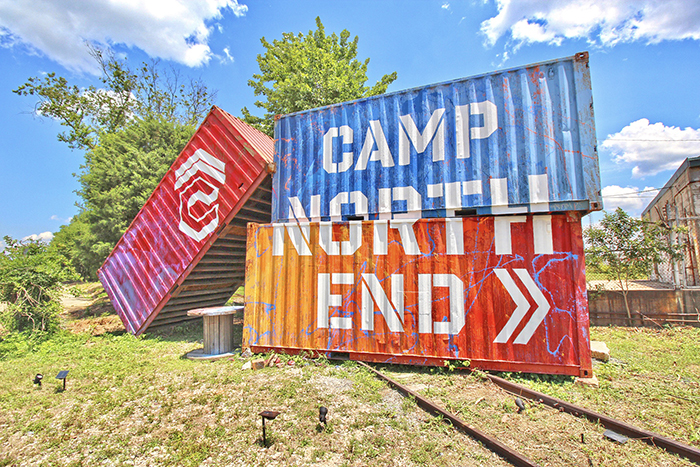 Three shipping crates painted red blue and orange Camp North End and the logo painted on the front
