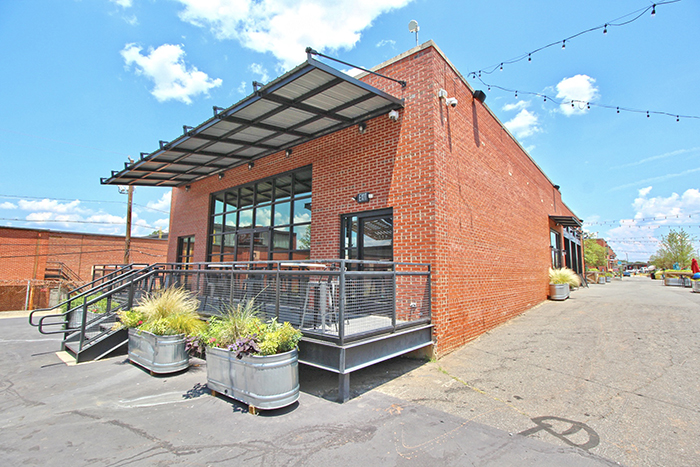 Brown brick building with covered porch and eating area string lights on the side