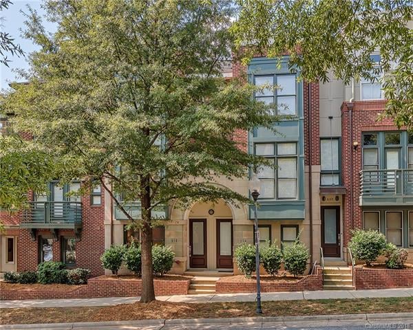 Red brick townhomes with green details on tree lined street
