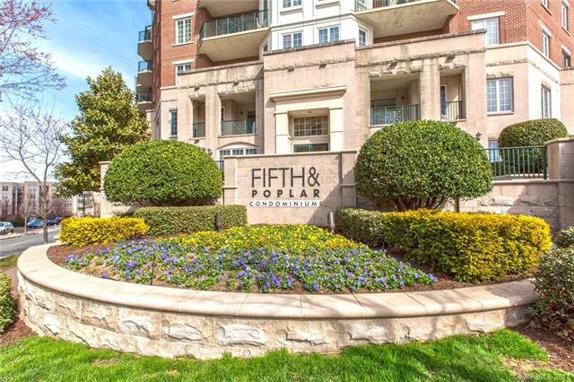 Condo building with red brick and stone details yellow and blue flowers planted around it