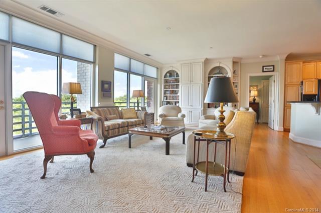 Living room with floor to ceiling windows light wood floors built in bookcases