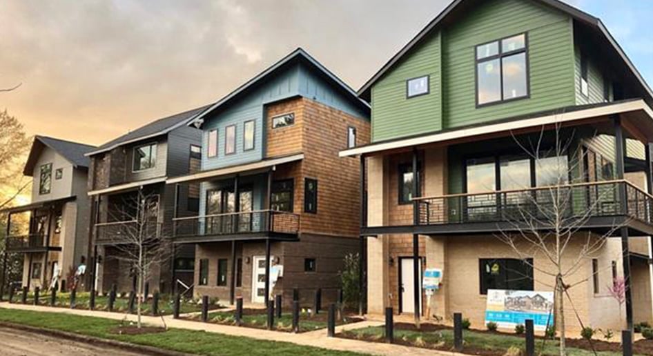 Four three story homes all a mix of colorful siding brick and wood with metal railing second story balconies