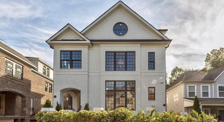 Duets at Brookside Three story white painted brick home with black trim windows and round window on the third floor and arched entryway to the front porch