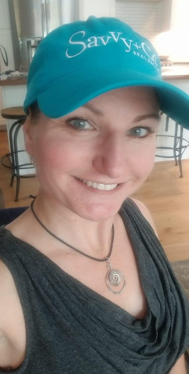 Shannon Lynch wearing a gray sleeveless blouse and a blue Savvy and Co Real Estate baseball cap