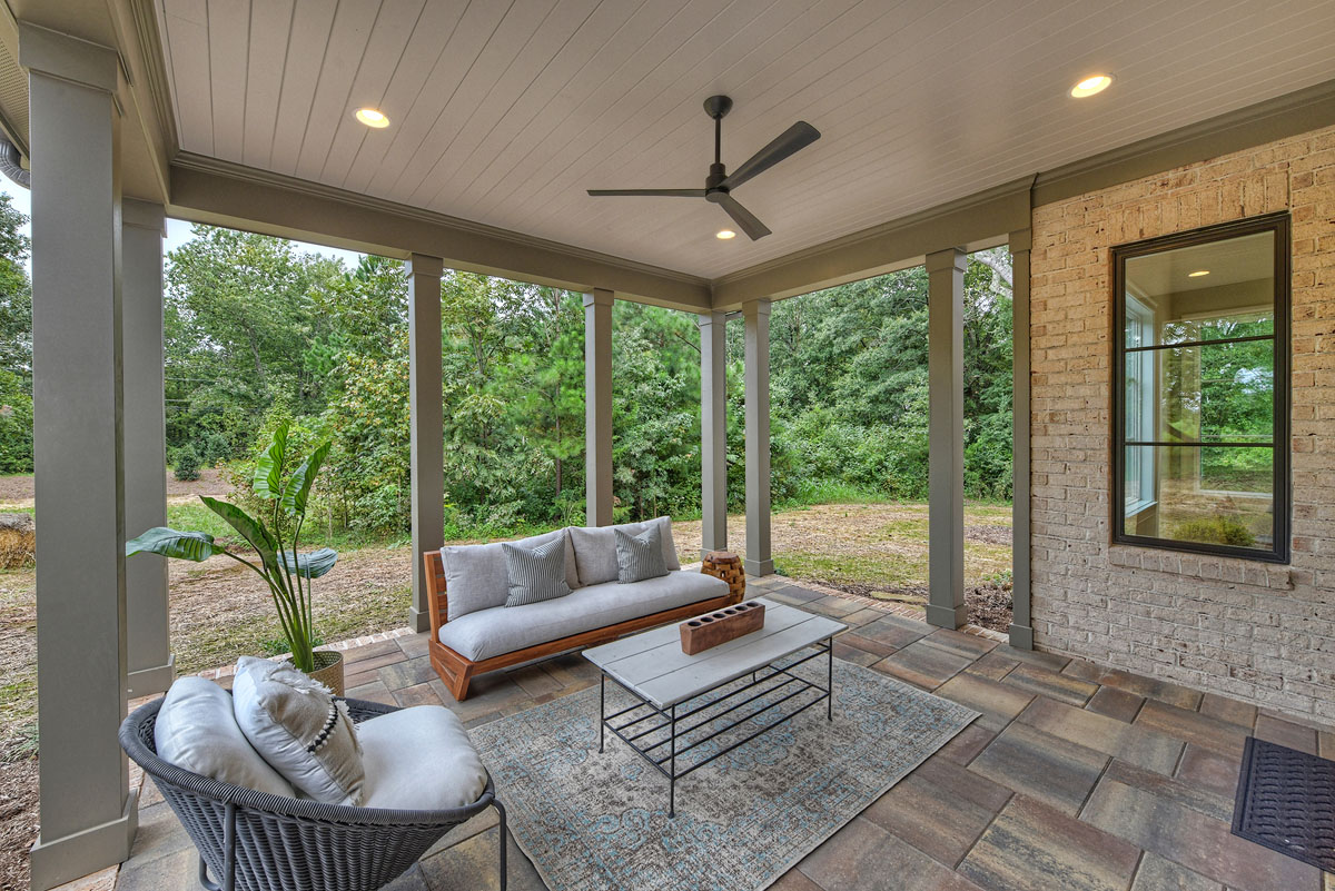 Back porch with cement tile flooring with brick trim and covered wood slat ceiling with recessed lighting and black ceiling fan